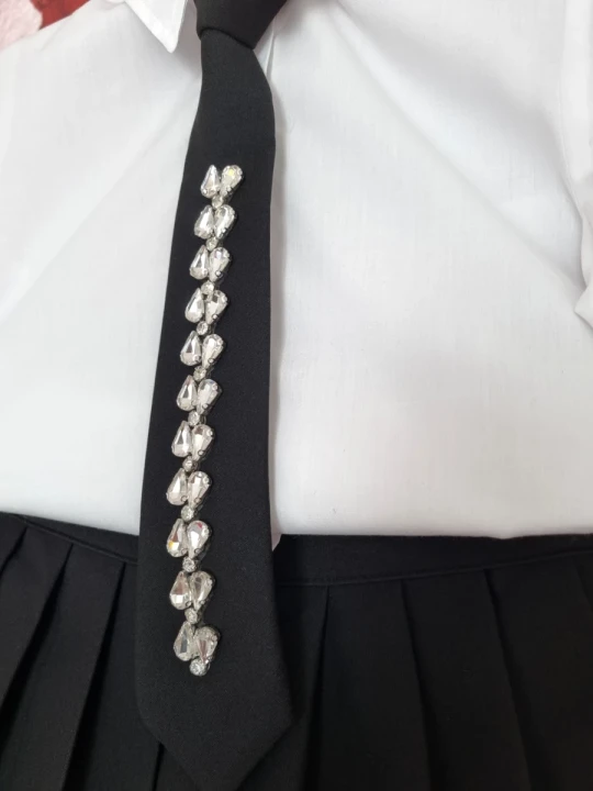 Elegancki biało czarny strój galowy, biała koszula z krawatem i czarna plisowana spódnica